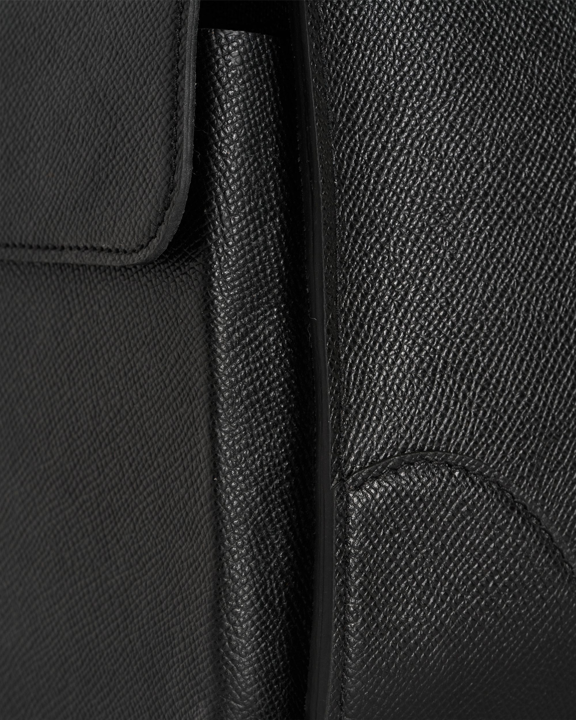 Gros plan sur le grain du cuir noir et une couture.