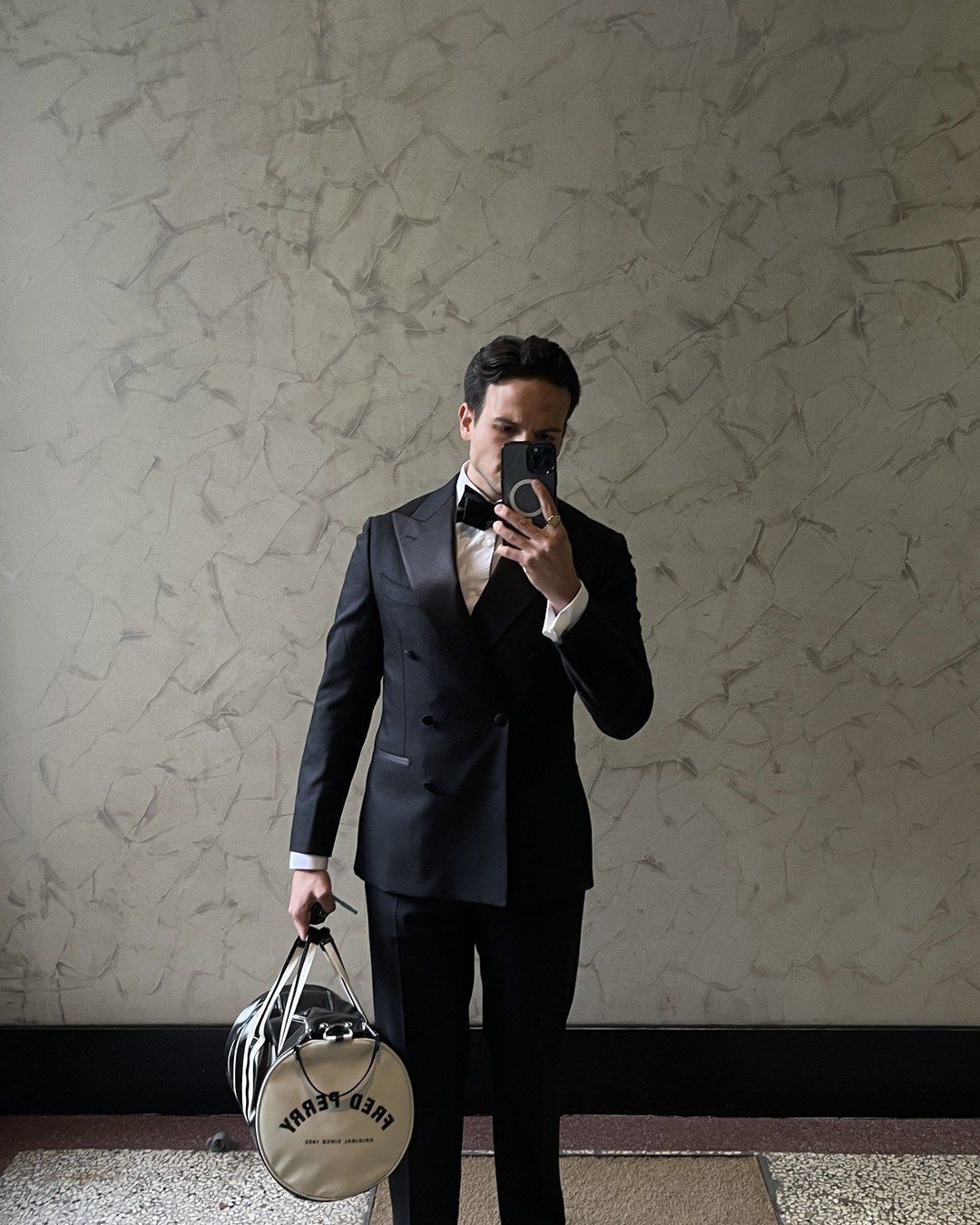 Samuel en smoking devant un miroir, un sac de sport ordinaire à la main.