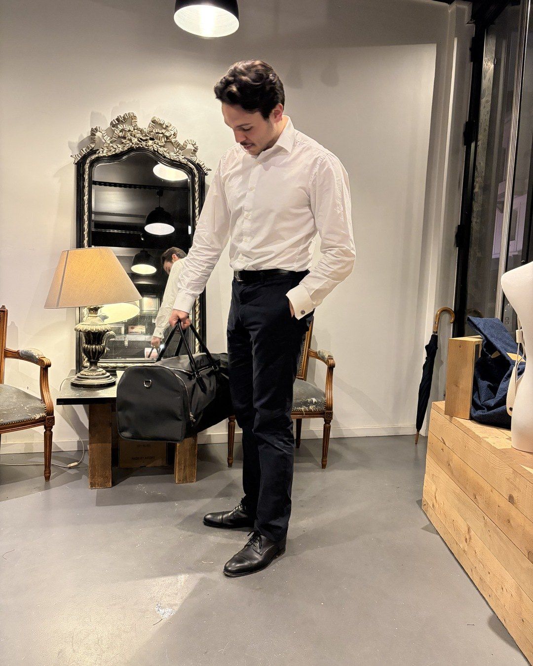 Un homme en chemise blanche saisit son Baisenville posé sur une table.